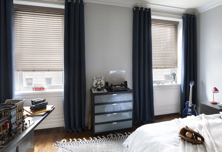 Rideaux en velours bleu associés à des stores en aluminium beige dans une chambre d'enfants moderne.