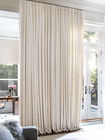 Rideaux crème du sol au plafond couvrant tout un mur de fenêtres et portes-fenêtres dans un salon élégant.