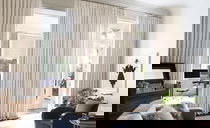 Rideaux crème du sol au plafond couvrant tout un mur de fenêtres et portes-fenêtres dans un salon élégant.