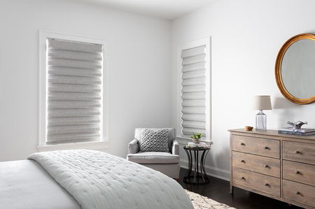 Stores romains à pli classique gris clair couvrant deux fenêtres dans une chambre moderne.