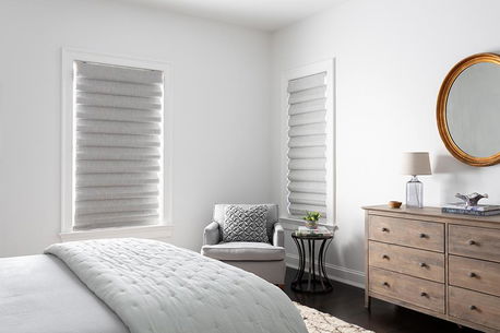 Stores romains à pli classique gris clair habillant deux fenêtres dans une chambre moderne
