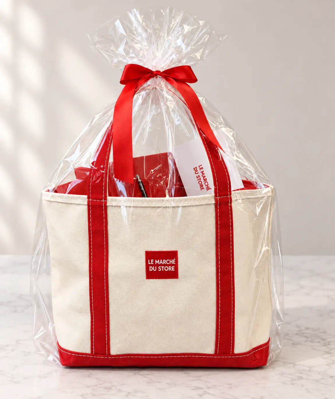 Canvas tote bag with red trim wrapped in cellophane and a red ribbon