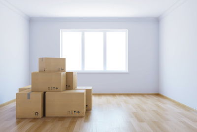 Une pièce vide avec des boîtes de déménagement présente une fenêtre sans habillage de fenêtre