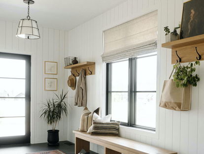 Les stores romains habillent une grande fenêtre de vestiaire d’entrée dans une maison de style champêtre moderne. Les stores romains habillent une grande fenêtre de vestiaire d’entrée dans une maison de style champêtre moderne.