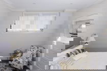 Stores en bois sur mesure dans une chambre avec deux petites fenêtres, offrant style et contrôle durable.