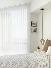 Les voilages verticaux offrent intimité le jour sans bloquer la vue sur une grande fenêtre de chambre moderne